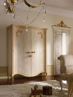 an ornate white armoire in a room with gold trimmings and chandelier