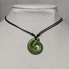 a green necklace on a mannequin neck with a circular pendant hanging from it