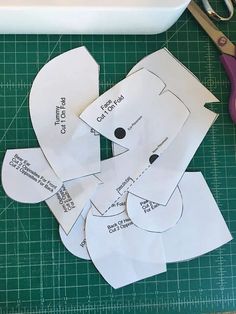 cut out pieces of paper sitting on top of a green cutting mat next to scissors