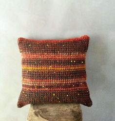 a brown and orange pillow sitting on top of a wooden stump