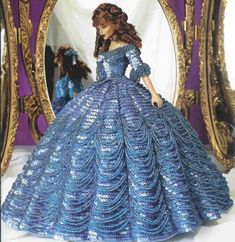 the doll is wearing a blue dress and standing in front of a mirror