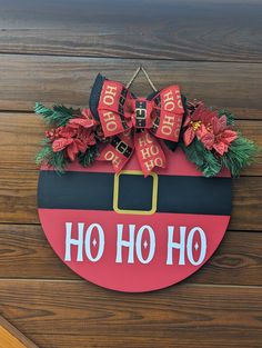 a red and black christmas sign hanging on a wooden wall with poinsettis