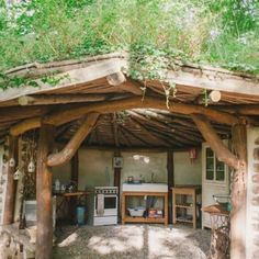 an outdoor kitchen is built into the side of a log structure with plants growing on top