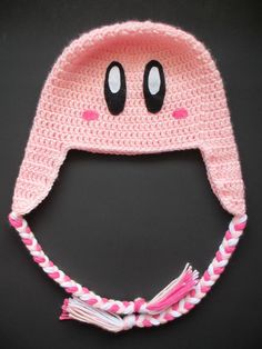 a crocheted pink hat with eyes and braids