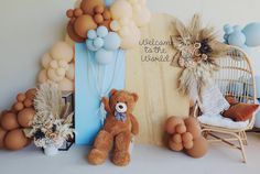 a teddy bear sitting in front of a wall with balloons and decorations on it's sides