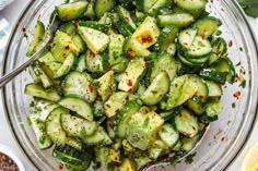 a glass bowl filled with cucumbers and seasoning on top of a table