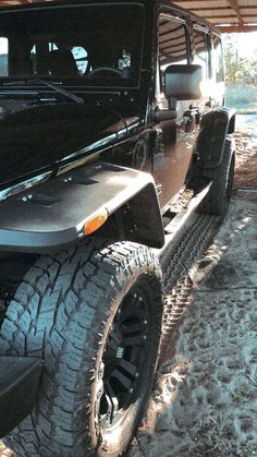 a black jeep parked in the snow under a roof area with no one around it