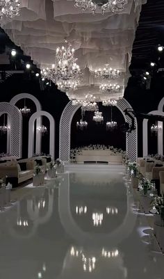 an elegant wedding setup with chandeliers and white flowers on the tables in front of it