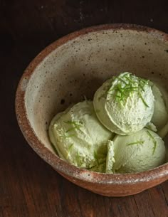 a bowl filled with green ice cream on top of a wooden table