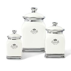 three white canisters with metal lids and silver trim on the sides, one has a