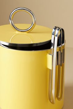 a close up of a yellow pot with a metal ring on the lid and handle