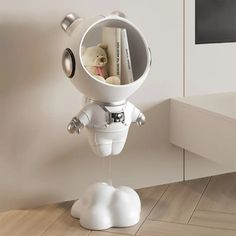 a small white space suit with a teddy bear in it's mouth, hanging from the side of a wall