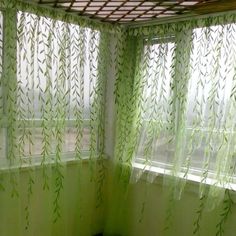 the curtains are hanging in front of the window with green leaves on them and one is closed