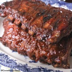 a plate with some meat on it and sauce in the middle, sitting on a blue and white plate