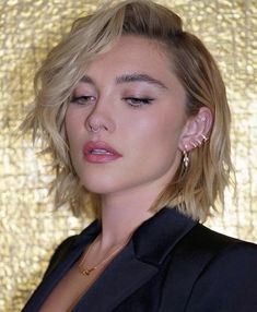 a close up of a person wearing a suit and earring on a gold background