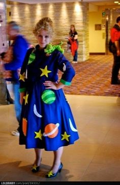 a woman in a blue dress with stars and planets on it, posing for the camera