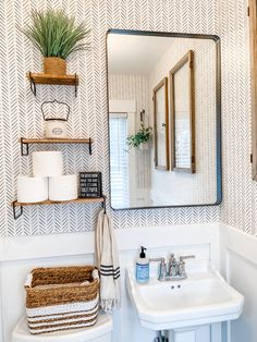 a bathroom with a sink, mirror and shelves on the wall next to the toilet