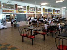 there are many people sitting at tables in the cafeteria