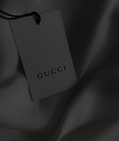 a tag that says gucci on it is hanging from the side of a bed