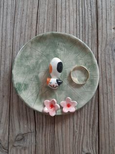 a ceramic plate with flowers on it and a ring holder in the shape of a flower