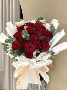 a person holding a bouquet of red roses