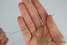 two hands are holding thread in one hand and the other hand is pointing at it