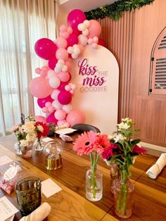 the table is set up with flowers and balloons in vases, along with other decorations