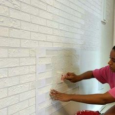 a woman painting a brick wall with white paint