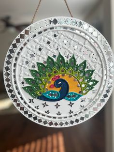 a white plate with a peacock on it hanging from a string in front of a window