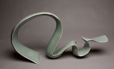 an artistic sculpture made out of clay on a gray background with the shape shaped like a bird