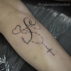 a tattoo on the arm of a woman that has a cross and hearts in it