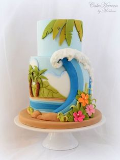 a colorful cake decorated with palm trees, waves and flowers on a white pedestal against a backdrop