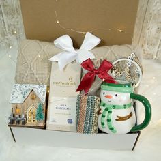 a gift box filled with christmas items including a snowman mug, cookies and candy