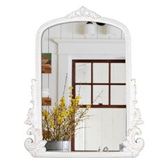 a white mirror sitting on top of a wooden table next to a vase filled with flowers