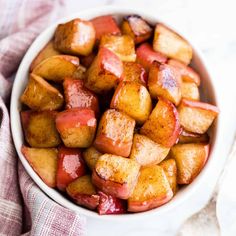 a white bowl filled with cubed potatoes on top of a pink and white checkered cloth