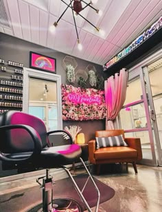 the salon has two chairs in front of it and a pink chair on the floor