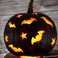 a carved pumpkin with bats and stars on it's face, sitting on a table