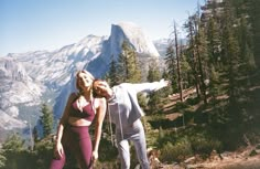 two women are posing in front of a mountain