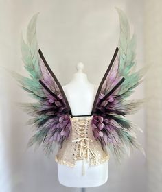 a white mannequin with purple and green wings on it