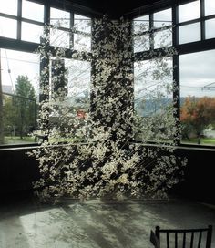 a room with large windows that have white flowers on the wall and in between them is a chair