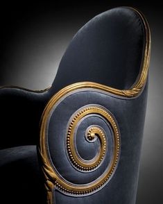 the back end of a blue chair with gold accents on it's armrests