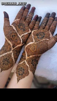 two hands with henna tattoos on them, one is showing off the intricate design