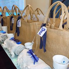 several bags are lined up on a table with blue ribbons and tags attached to them