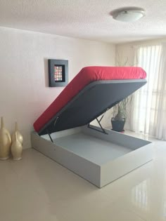 a bed that is in the middle of a room with a red pillow on it