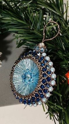 an ornament hanging from a christmas tree with blue and white beads on it