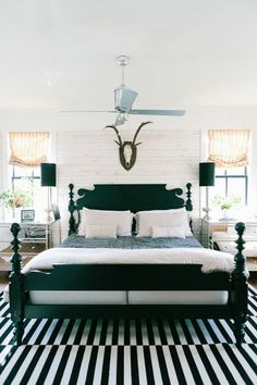 a bedroom with black and white striped flooring and a bed in front of a ceiling fan