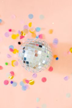 a disco ball is surrounded by confetti and streamers on a pink background