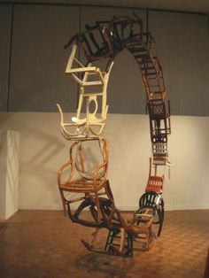 three wooden chairs stacked on top of each other in front of a white wall and ceiling