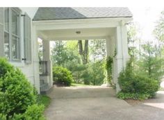 an entrance to a white house surrounded by trees