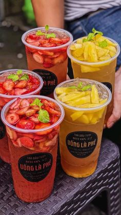 four plastic cups filled with different types of fruit and veggies on top of a table